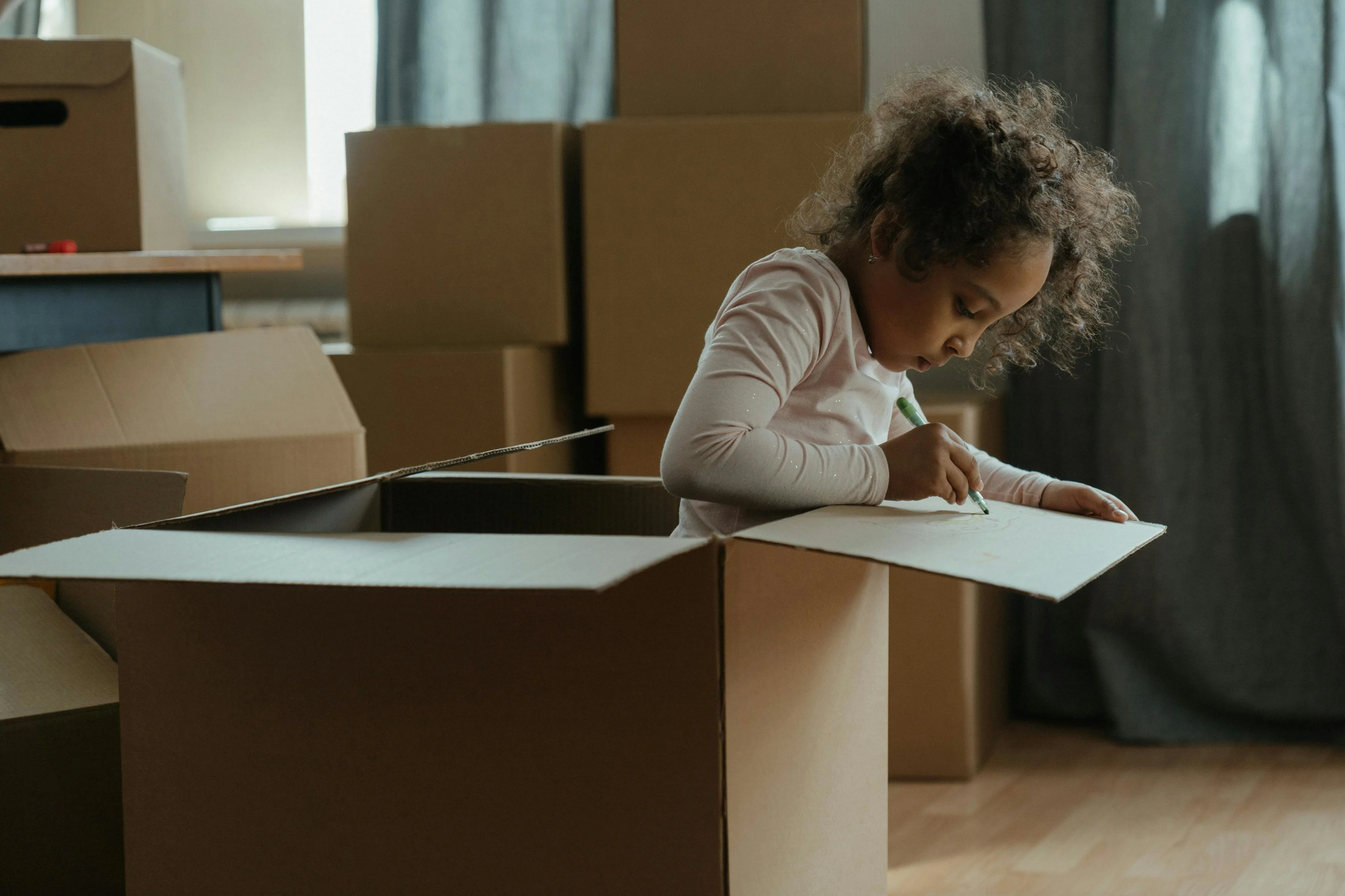 A child drawing on a cardboard box during a move.